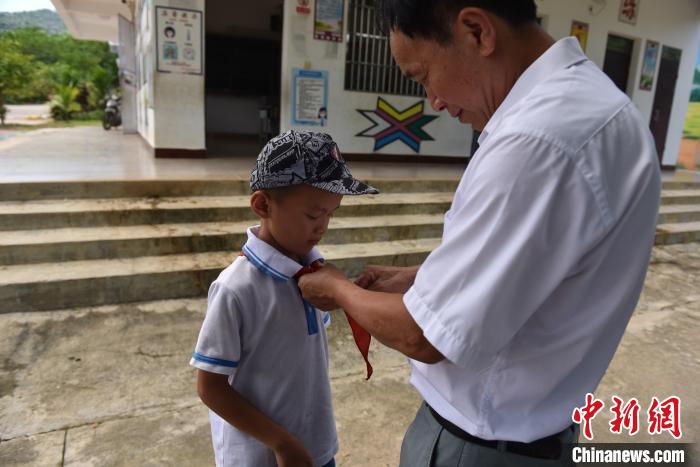 李修雄在给学生系红领巾。 林小丹 摄