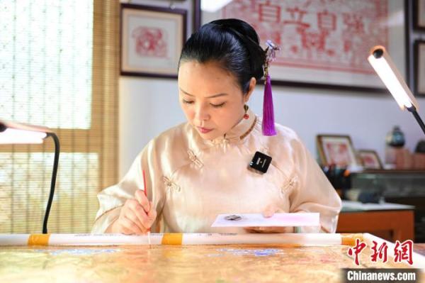饶宝莲给铜凿剪纸上色。 陈骥旻 摄